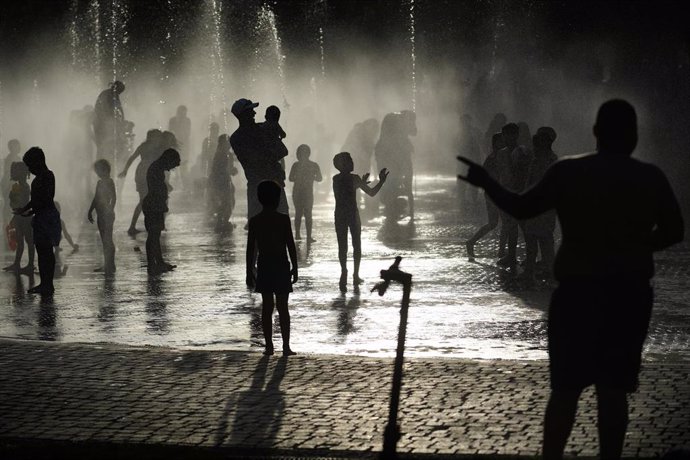 Grupos de personas disfrutan en la fuente transitable conocida popularmente como los chorros o la playa de Madrid Río.