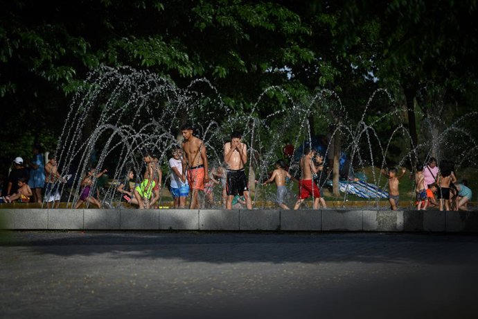 Grupos de personas disfrutan en la fuente transitable conocida popularmente como los chorros o la playa de Madrid Río, a 12 de junio de 2022, en Madrid (España). La llegada de la primera ola de calor del verano de 2022 ha puesto en riesgo a varias comun