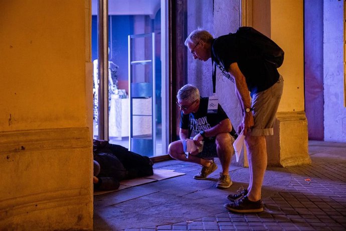 Dos voluntarios se interesan por una persona durante la realización del censo de personas en situación de sinhogarismo llevado a cabo por la fundación Arrels, a 15 de junio de 2022, en Barcelona