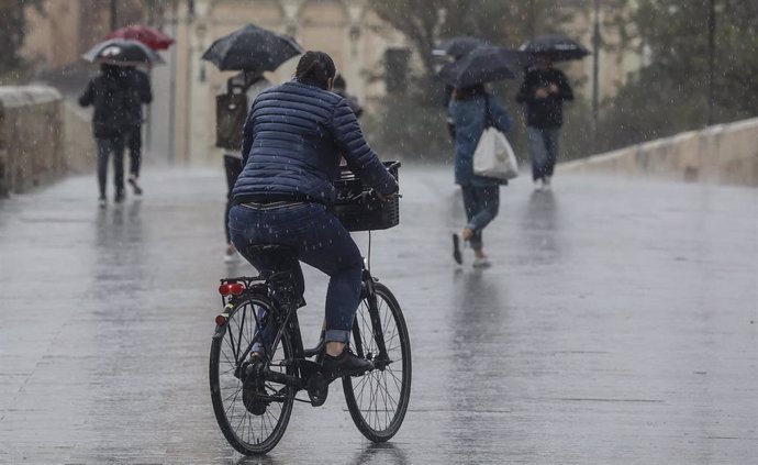 Archivo - Una persona circula en bicicleta bajo la lluvia