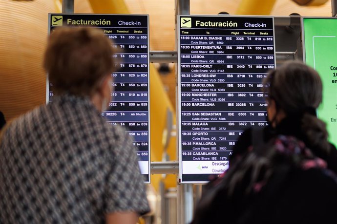 Dos personas miran el panel de facturación de la Terminal 4 (T4) del aeropuerto Adolfo Suárez Madrid-Barajas, a 8 de junio de 2022, en Madrid, (España).  