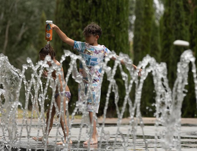 Dos niños se mojan entre ellos en los chorros por el calor (archivo).