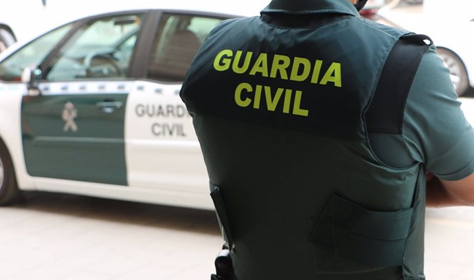 Un agente de la Guardia Civil, de espaldas, junto a un vehículo oficial
