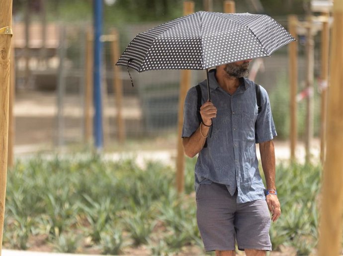 Un hombre pasea con paraguas por la ola de calor