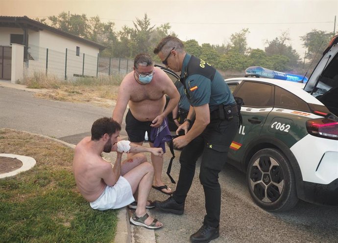 Un guardia civil atiende a un vecino herido que ayuda en las labors de extinción del  incendio declarado en Obanos, a 18 de junio de 2022, en Obanos.