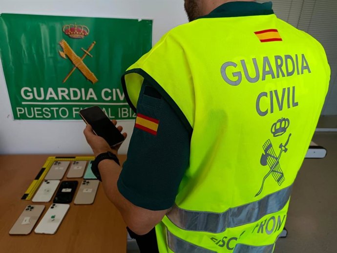 Un agente de la Guardia Civil con los móviles incautados.