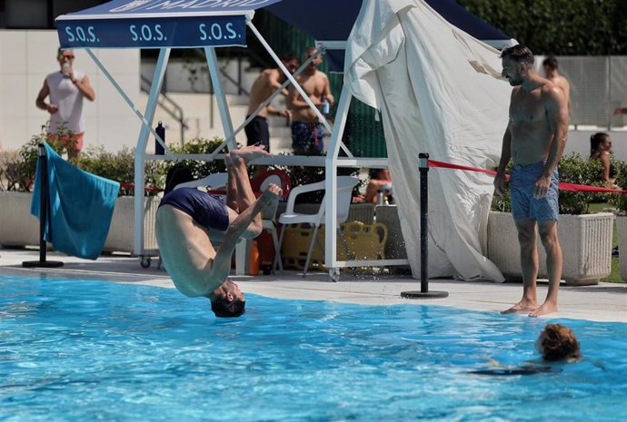 Un hombre se tira de cabeza al agua en la piscina municipal de Casa de Campo
