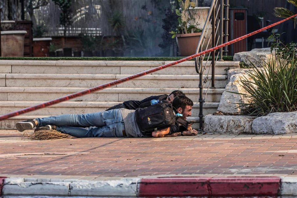 Archivo - Dos israelíes se protegen después de que saltara una alarma antiaérea en Sderot en 2019