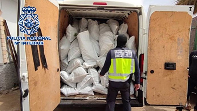 Un agente ante una furgoneta cargada con sacos de marihuana.