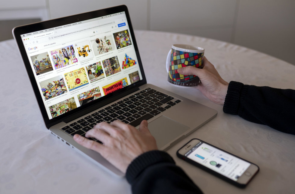 Una persona compra con su teléfono móvil y ordenador 