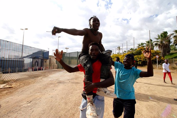 Varios migrantes se dirigen al Centro Temporal de Inmigrantes (CETI), mientras celebran el salto de la valla de Melilla, a 24 de junio de 2022, en Melilla (España). El grupo de migrantes está formado por más de 400 subsaharianos, que han accedido a Meli