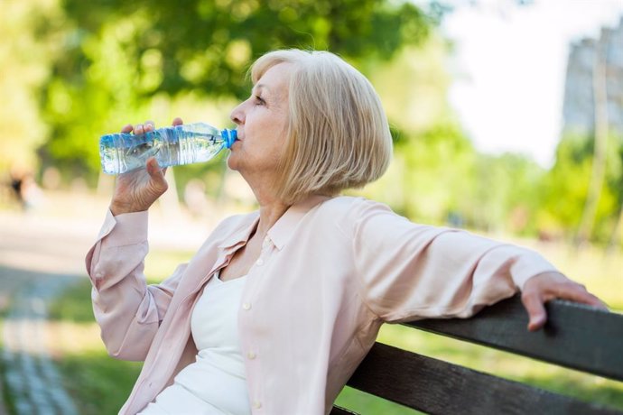 Mujer bebiendo agua en un parque.
