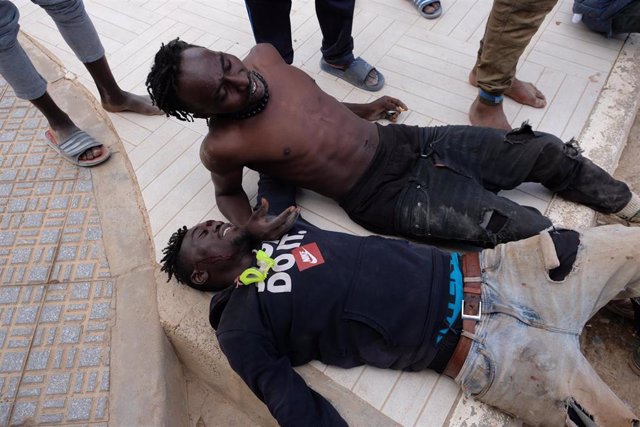 Dos migrantes descansan tras saltar la valla de Melilla, a 24 de junio de 2022, en Melilla (España)
