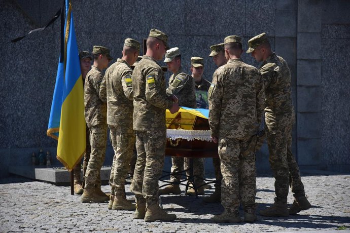 07 June 2022, Ukraine, Lviv: Ukrainian military personnel cover the Ukrainian flag on the coffin with the body during the farewell ceremony for the fallen soldier. Ukrainian soldier Anton Velychko, who died May 23 in a skirmish with Russian troops near 