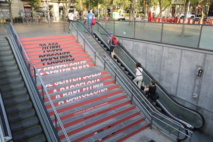 Un vinilado en un acceso al metro por la campaña del Ayuntamiento de Barcelona 'Contra la soledat, reconnectem'
