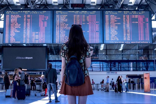 Una joven turista visualiza el panel que muestra los vuelos programados en un aeropuerto.