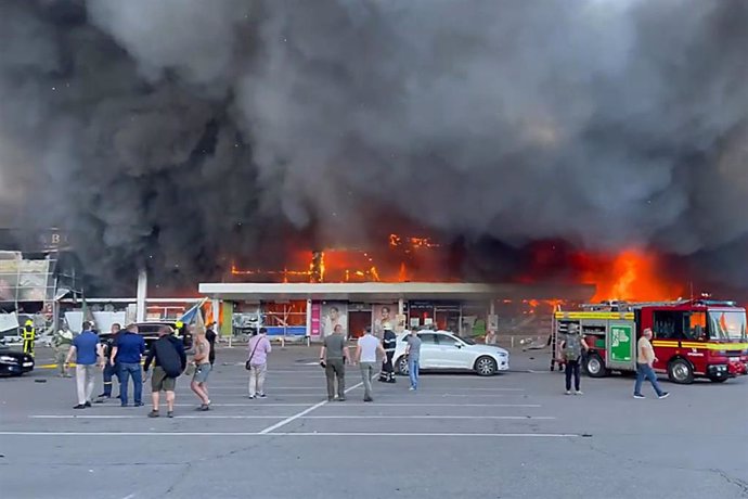 Los bomberos trabajan para apagar el fuego en un centro comercial afectado por un ataque de misiles rusos en la ciudad ucraniana oriental de Kremenchuk