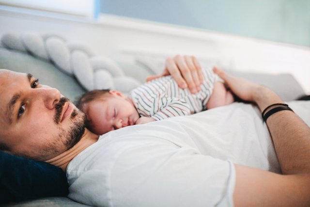 Archivo - Padre con bebé durmiendo.