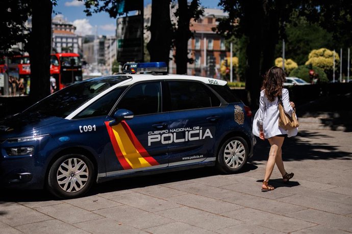 Una mujer pasa al lado de un coche de la Policía Nacional aparcado en Madrid.