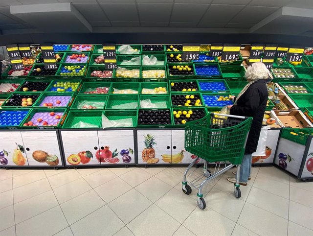 Archivo - Un mujer coloca fruta en una bolsa mientras observar los productos que quedan en las cajas de un supermercado un día marcado por colas de gente deseosas de hacer acopio de alimentos y otros productos debido al avance del coronavirus en España, e