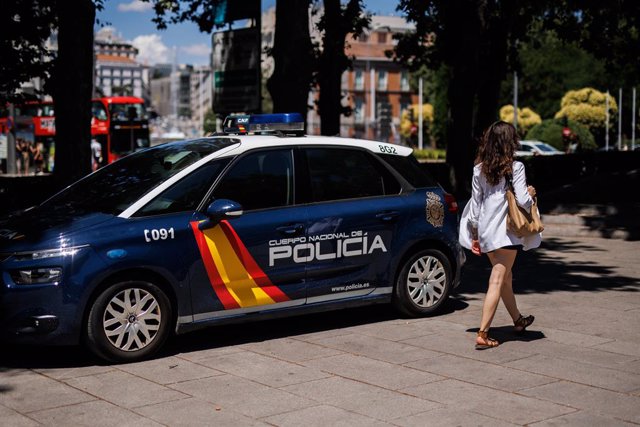 Una mujer pasa al lado de un coche de la Policía Nacional aparcado en el centro de la capital un día antes del inicio de la OTAN, a 27 de junio de 2022, en Madrid (España). 