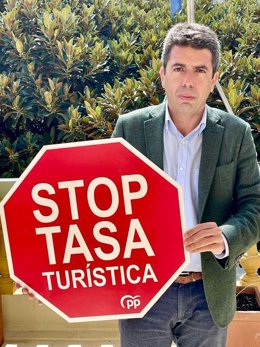 Archivo - El presidente del PPCV, Carlos Mazón, con un cartel de la campaña 'Stop a la tasa turística'