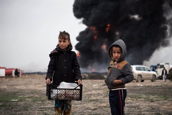 Archivo - Niños llevan comida a los bomberos mientras intentan extinguir los pozos de petróleo incendiados por los miembros de ISIS mientras se retiraban en Irak, el miércoles 15 de marzo de 2017.