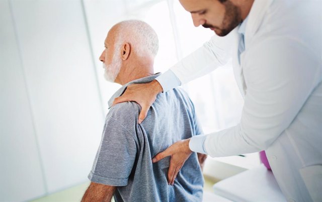 Archivo - Médico examina la espalda a un paciente mayor con dolor.