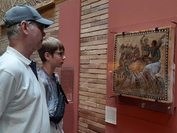 Dos visitantes contemplan el mosaico de una cuadriga victoriosa, pieza del Museo Arqueológico Nacional, que puede visitarse en una exposición temporal en el Museo Nacional de Arte Romano de Mérida.