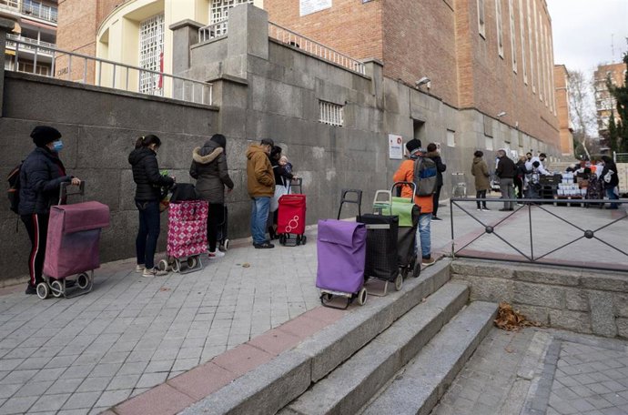 Archivo - Varias personas hacen cola para recibir alimentos en una imagen de archivo