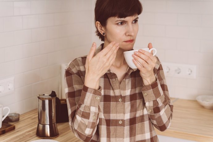 Archivo - COVID-19 causa pérdida de olor. Mujer oliendo olor a café de taza mientras prepara bebida