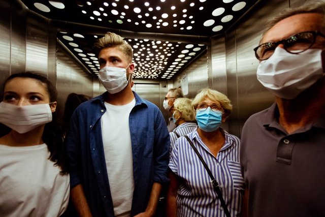 Ascensor, gente con mascarilla.