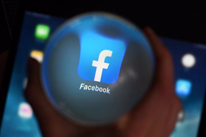 Archivo - FILED - 10 June 2020, Baden-Wuerttemberg, Karlsruhe: A person looks at the Facebook app through a glass ball on a tablet. Facebook's cybersecurity team has identified a state-backed hacking group in Vietnam by tracking them down to an IT firm 