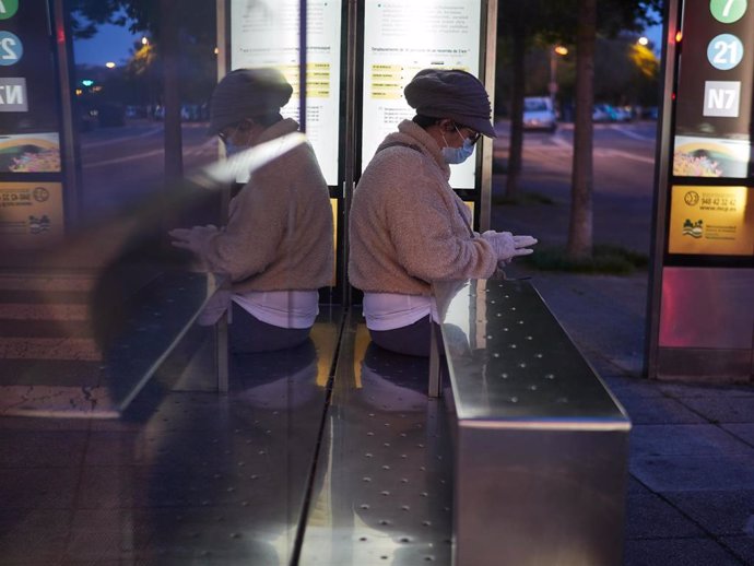 Archivo - Una mujer se protege con mascarilla mientras espera al autobús urbano en Pamplona.