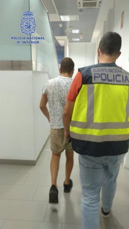 Un agente de la Policía Nacional escolta a uno de los detenidos.