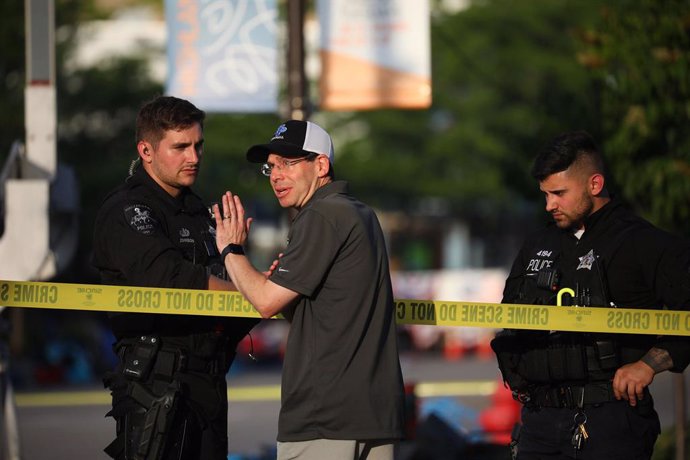 Los oficiales de policía hablan con un residente a lo largo de Central Avenue, cerca de la escena donde un perpetrador desconocido disparó durante un desfile del 4 de julio en Highland Park.