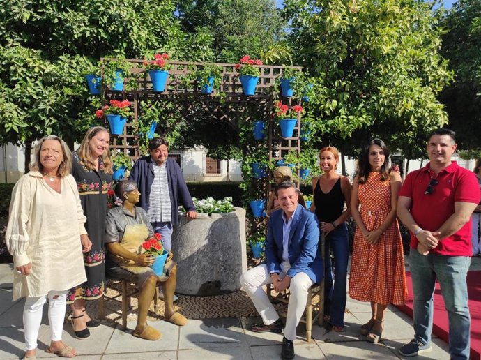 El alcalde (sentado), junto miembros de la Corporación municipal y el escultor (apoyado en el pozo).