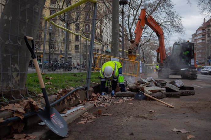 Archivo - Un obrero y una máquina excavadora trabajan en las obras para unir el tranvía por la Diagonal, a 7 de marzo de 2022, en Barcelona, Catalunya (España). 