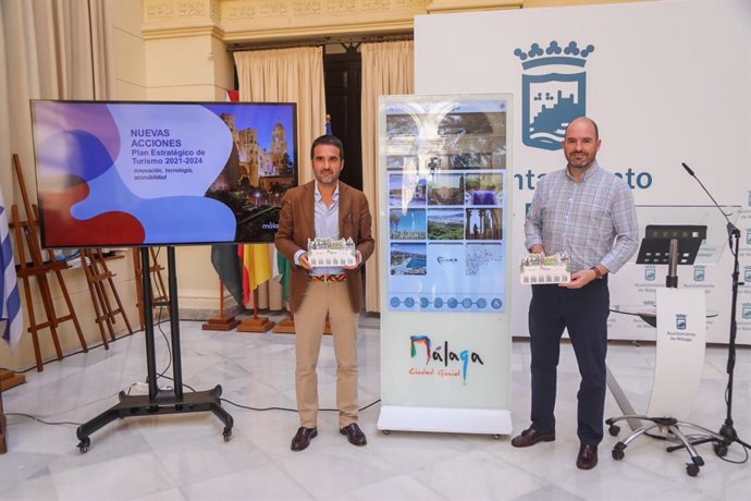El concejal de Turismo, Jacobo Florido, a la izquierda de la imagen, con un 'display' en sus manos como los que se distribuirán en los alojamientos y junto a uno de los tres soportes interactivos que se instalarán en la ciudad