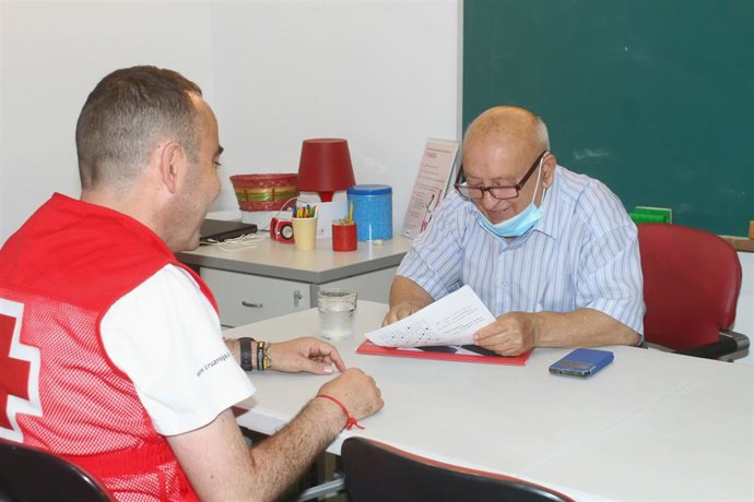 Un miembro de Cruz Roja atiende a una persona mayor.