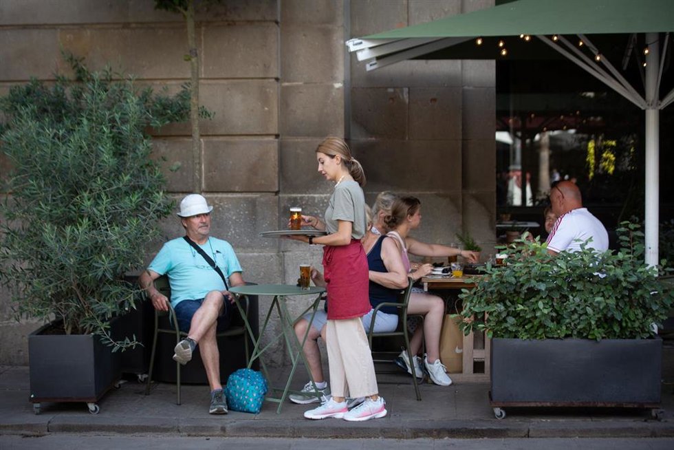 Una camarera sostiene una bandeja en una terraza