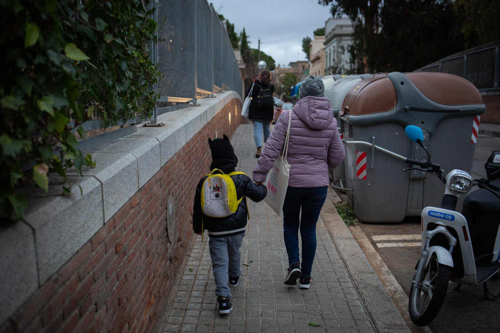 Una mujer lleva de la mano a un niño a su primer día de clase presencial tras la Navidad, a 10 de enero de 2022, en Barcelona, Catalunya, (España). 