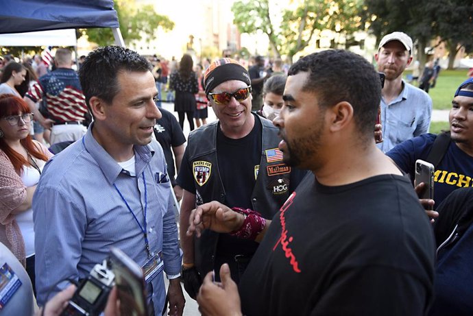 El candidato republicano a gobernador de Michigan Ryan Kelley (i) habla con un manifestante durante unas protestas.