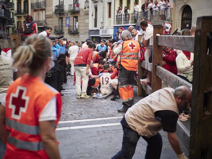 Cruz Roja atiende a un corredor herido en el tercer encierro de Sanfermines, con toros de José Escolar.