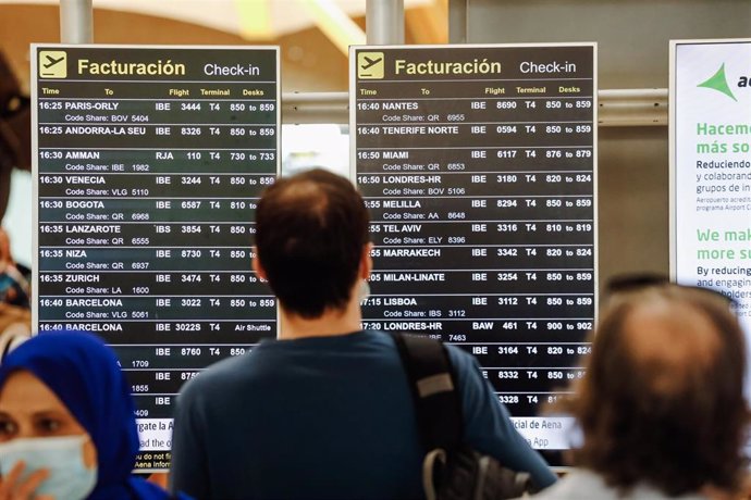 Pasajeros observan las pantallas con los vuelos de la Terminal 4 del Aeropuerto Adolfo Suárez Madrid Barajas  