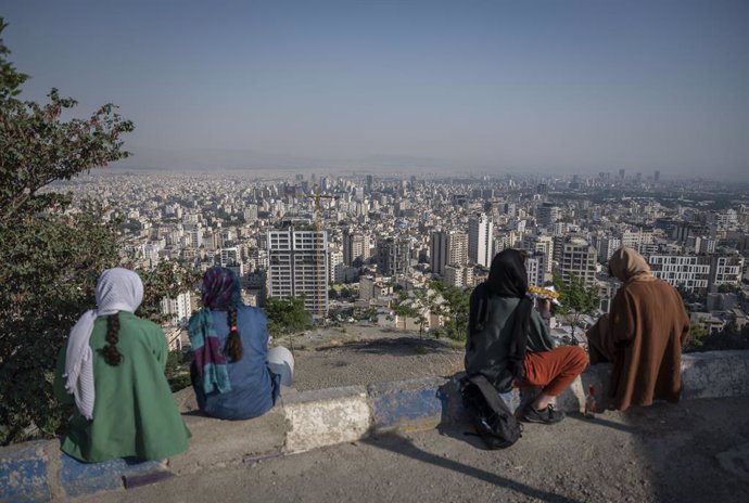 Archivo - 27 May 2022, Iran, Tehran: Young Iranian women sit by the "roof of Tehran" (Bam-e Tehran) and look out over the metropolis. Photo: Arne Bnsch/dpa