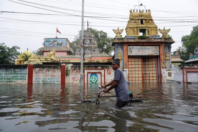 Archivo - Imagen de archivo en la que un hombre cruza una calle anegada por las fuertes lluvias en la región de Chennai, en el sur de India.