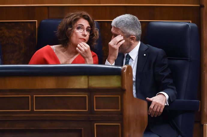 La ministra de Hacienda, María Jesús Montero, y el ministro del Interior, Fernando Grande-Marlaska, conversan en una sesión plenaria, en el Congreso