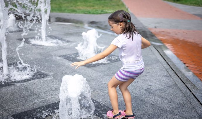 Niña se refresca en una fuente