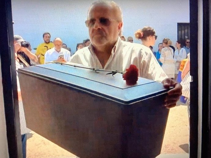 Un hombre porta una urna con los restos de uno de los represaliados en Valencia de Alcántara para enterrarlos en el cementerio municipal.